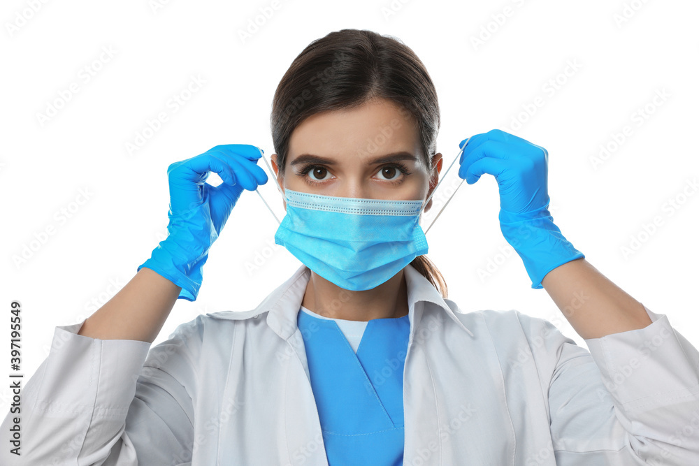 Doctor in medical gloves putting on protective mask against white background