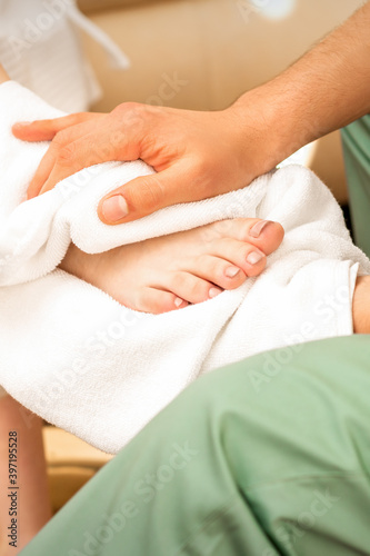 Masseur wiping the woman's legs after a foot massage in the spa salon