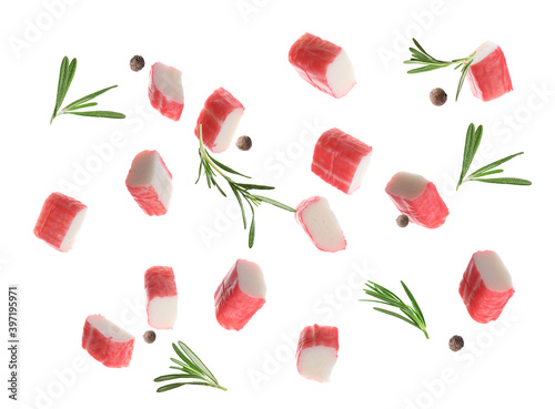 Foto Cut fresh crab sticks, rosemary and allspice falling on white background