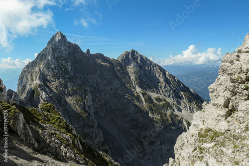 A panoramic view on Alpine slopes in Austria. There are sharp ans steep mountains and high peaks around. The Alpine slopes are almost barren, just moss overgrowing the slopes. Serenity and freedom.