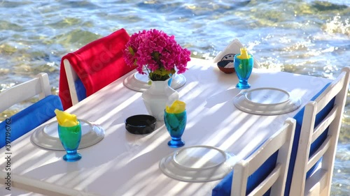 Aegean fish restaurant, table and chairs with bougainvillea flowers next to see in Bodrum, Turkey at sunny day. It is very famous and attraction point for tourist in Bodrum.