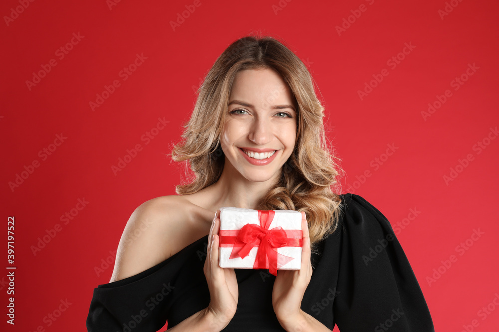 Beautiful young woman with Christmas present on red background Beautiful young woman with Christmas present on red background
