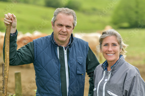 Portrait of a farmer couple standing outdoors in front of their cattle  in their cows farm