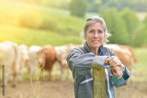 Portrait of a smiling cattlewoman standing beside her cows