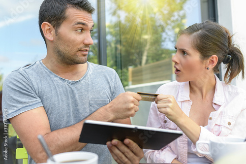 Couple talking and buying something online with a tablet outdoors