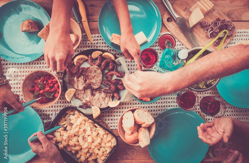 Top view of friends eating together food on the table in friendship celebration - family enjoy drink and lunch having fun - coloured rustic wooden table with blue dishes