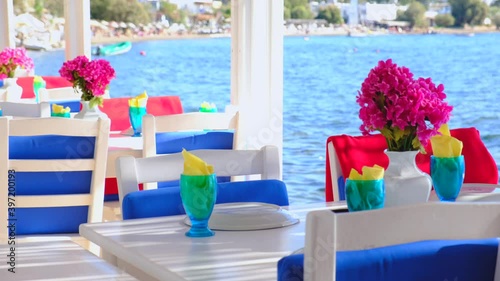 Aegean fish restaurant, tables and chairs with bougainvillea flowers next to see in Bodrum, Turkey at sunny day. It is very famous and attraction point for tourist in Bodrum.