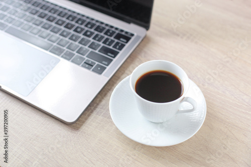 A coffee cup with laptop on the wooden office desk