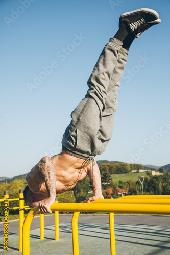 Young urban athlete doing a diagonal handstand on parallel bars at a calisthenics gym