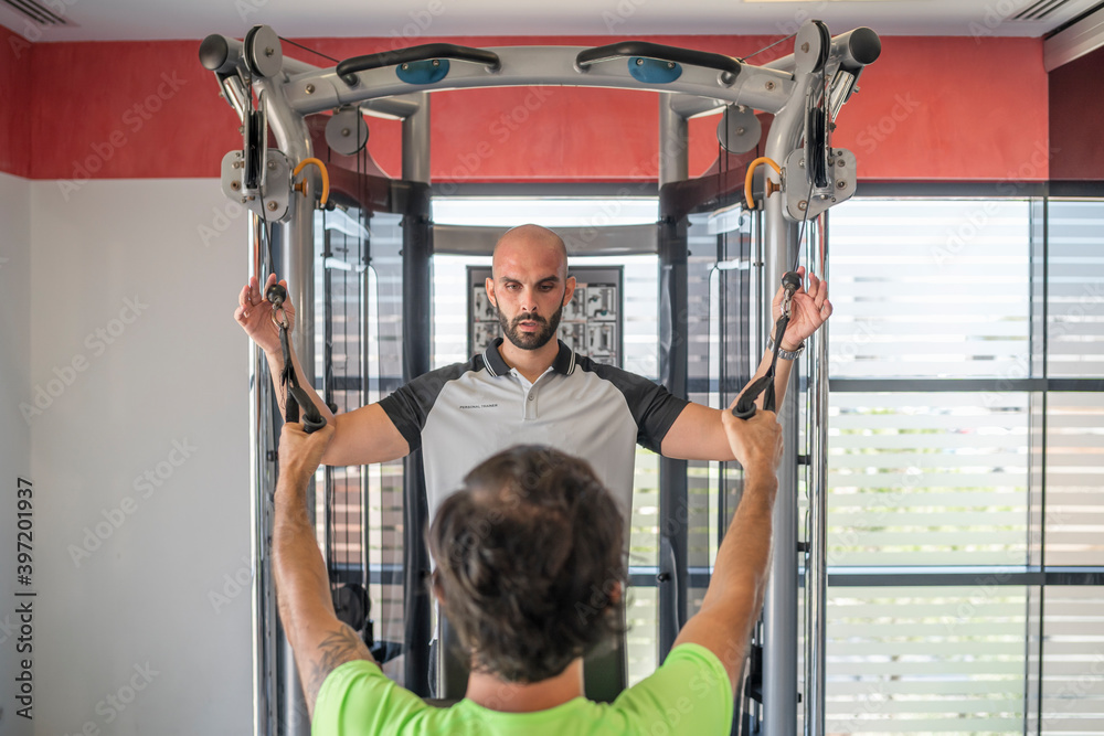 Personal trainer exercising on the machine with his client Personal trainer exercising on the machine with his client