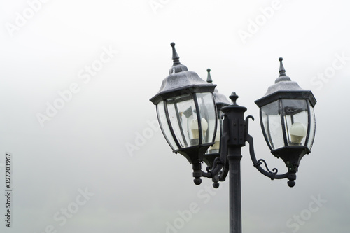Abandoned old street lamp with curved lampshades in a gloomy gray morning. Copy space on white background
