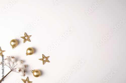 Flat lay. New year and christmas theme. A twig with white snow-covered berries, golden Christmas balls and stars. White background.