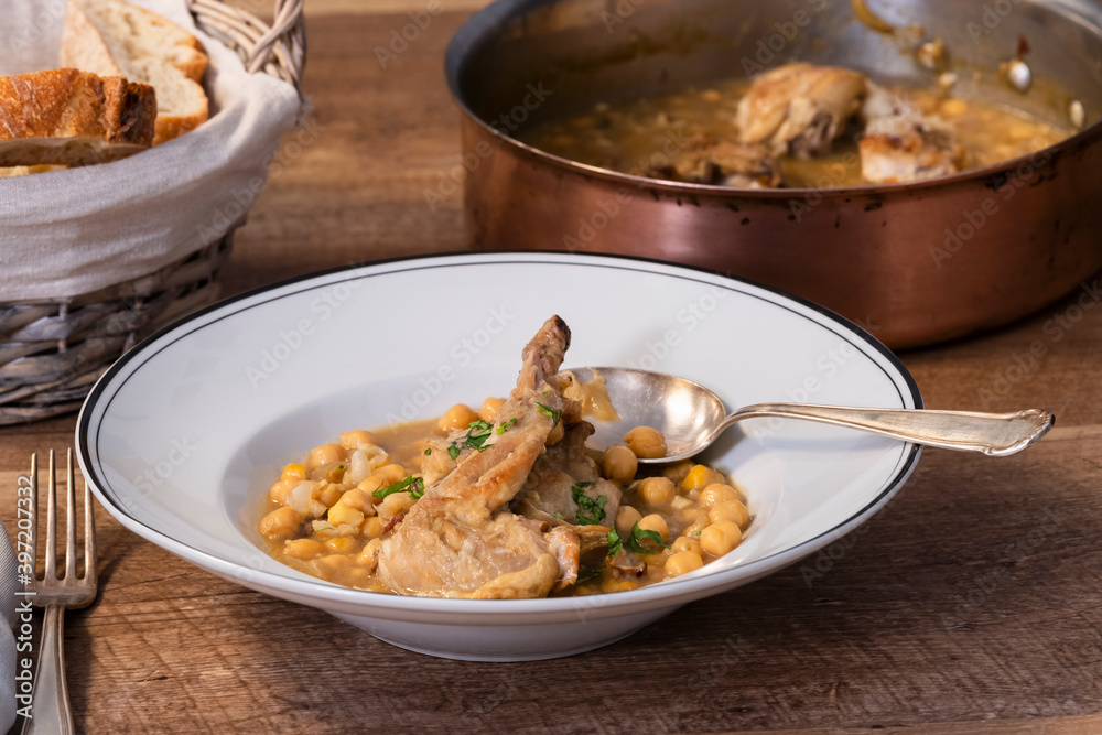 close up of a delicious looking plate of chickpea and meat stew with a spoon on a wooden table close up of a delicious looking plate of chickpea and meat stew with a spoon on a wooden table