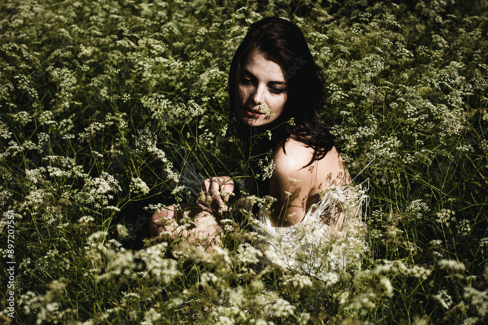 Young woman with black hair and naked back among wildflowers