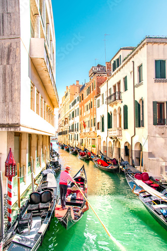 Summer in Venice, Italy. View of old buildings, narrow streets and bridges. Monuments of one of the most beautiful cities in Italy. On the picture there is gondolier with oar