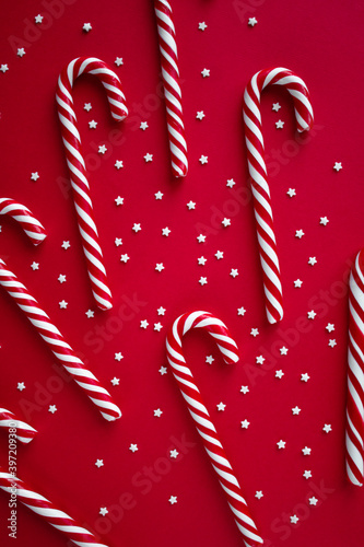 Christmas vertical background with candy canes. Red sweet sticks with small stars. Flat lay, overhead view. Poster, banner, greeting card template. Festive backdrop. Holiday season