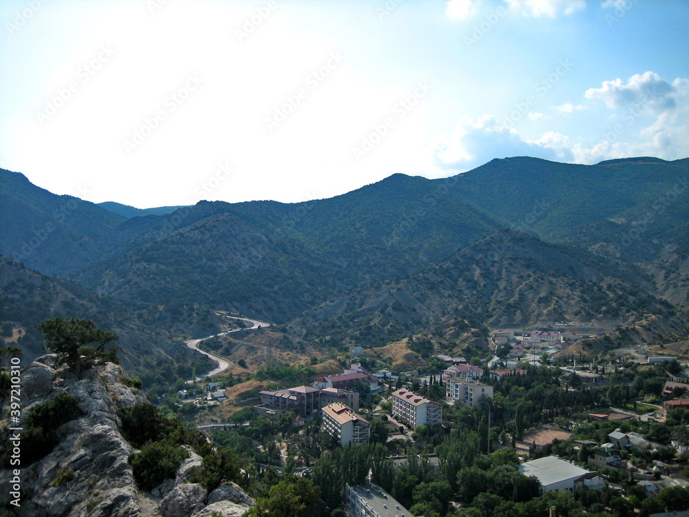 Gorgeous view of a small town surrounded by high rocky mountains. The city built on the hillsides and in the valley. Gorgeous view of a small town surrounded by high rocky mountains. The city built on the hillsides and in the valley.