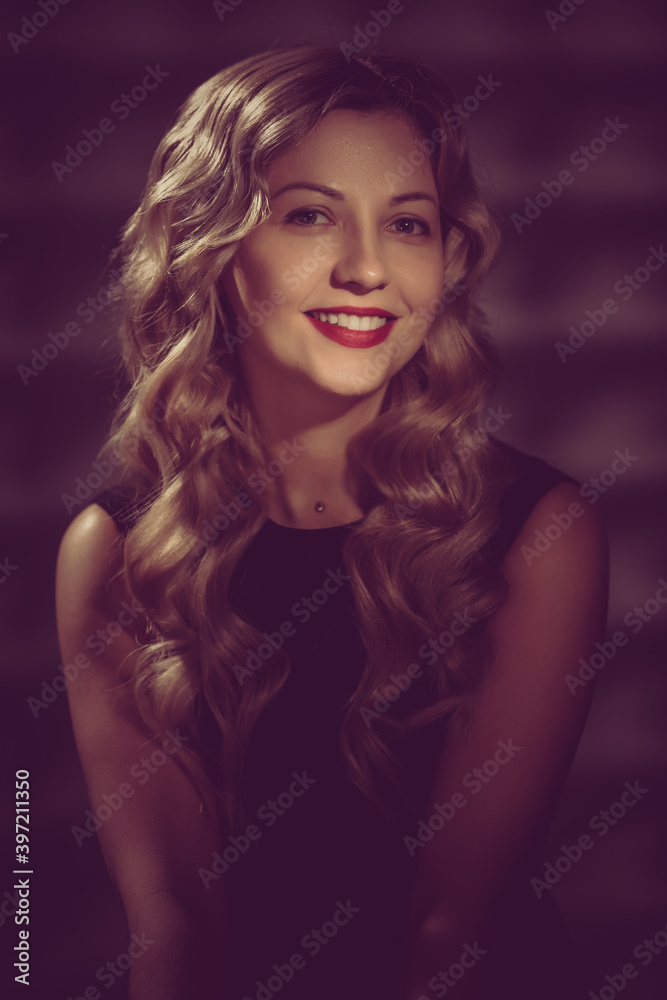 Beautiful smiling model with wavy hairstyle posing in black dress. image toned in warm colors in retro style Beautiful smiling model with wavy hairstyle posing in black dress. image toned in warm colors in retro style