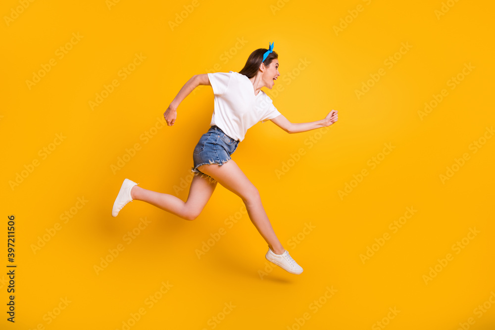 Fototapeta premium Full length body size side profile photo of girl running fast jumping high yelling isolated on vibrant yellow color background