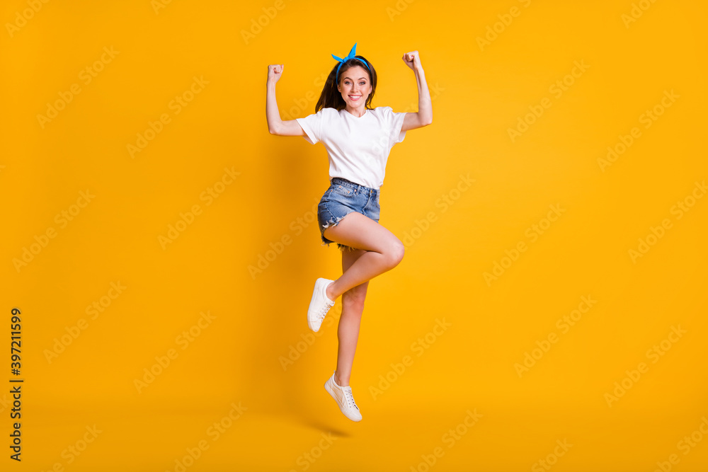 Full length body size photo of girl demonstrating strong hands muscles biceps jumping high on vivid yellow color background