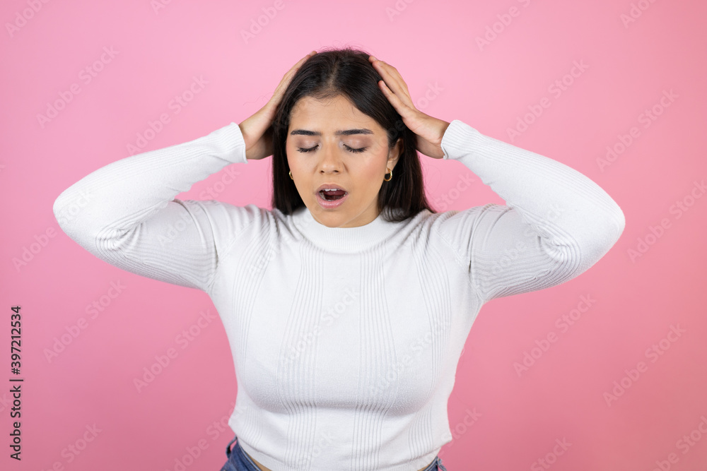 Young beautiful woman over isolated pink background suffering from headache desperate and stressed because pain and migraine with her hands on head Young beautiful woman over isolated pink background suffering from headache desperate and stressed because pain and migraine with her hands on head