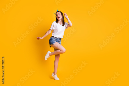 Full length body size view of slim pretty cheerful brown-haired girl jumping having fun dancing isolated over bright yellow color background