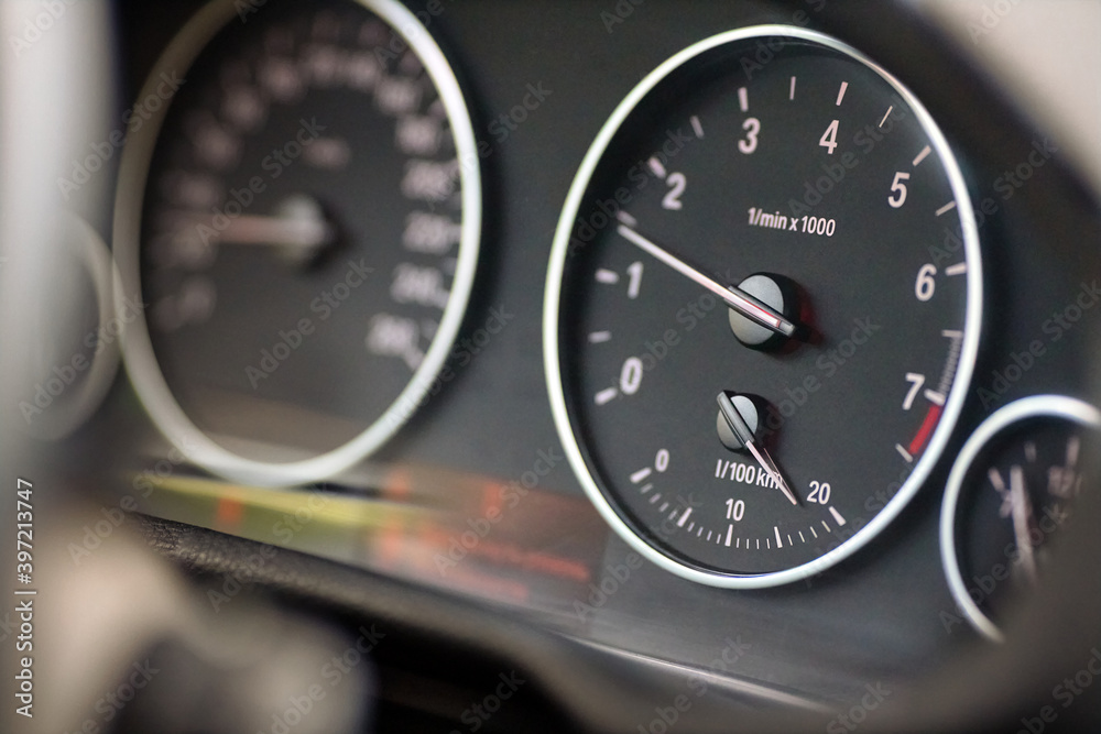 Rev counter of car selective focus closeup with copyspace. Tachometer or revolution counter, RPM gauge with red glowing needle on car dashboard with fuel and out of focus speed meter. Rev counter of car selective focus closeup with copyspace. Tachometer or revolution counter, RPM gauge with red glowing needle on car dashboard with fuel and out of focus speed meter.