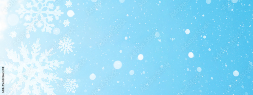 snowflakes isolated on blue sky illuminated by the sun - winter background panorama banner long