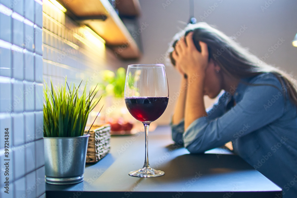 Lonely depressed drinking woman suffering from alcohol addiction abuse with red wine glass alone at home Lonely depressed drinking woman suffering from alcohol addiction abuse with red wine glass alone at home