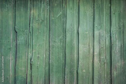 Vintage rustic background. House wall in the village. Large rough planks of green upright.