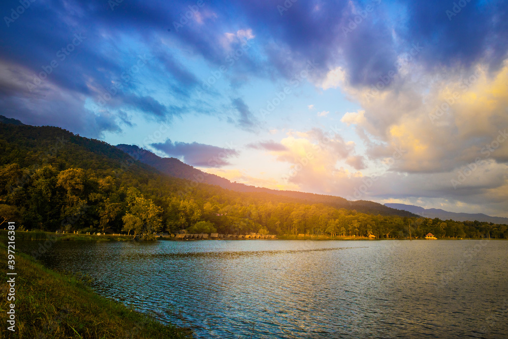 Mountains with blue sky and sunlight reflected on lake at sunset. Beautiful landscape nature scene on sunrise or  sunset in cloudy day.