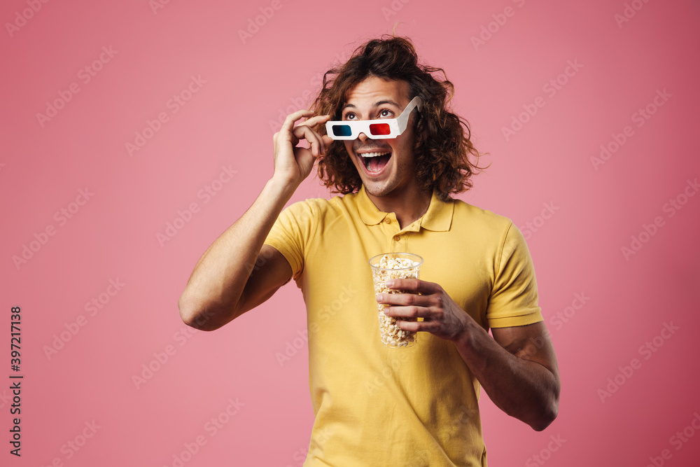 Excited handsome guy in 3d glasses eating popcorn while watching movie Excited handsome guy in 3d glasses eating popcorn while watching movie