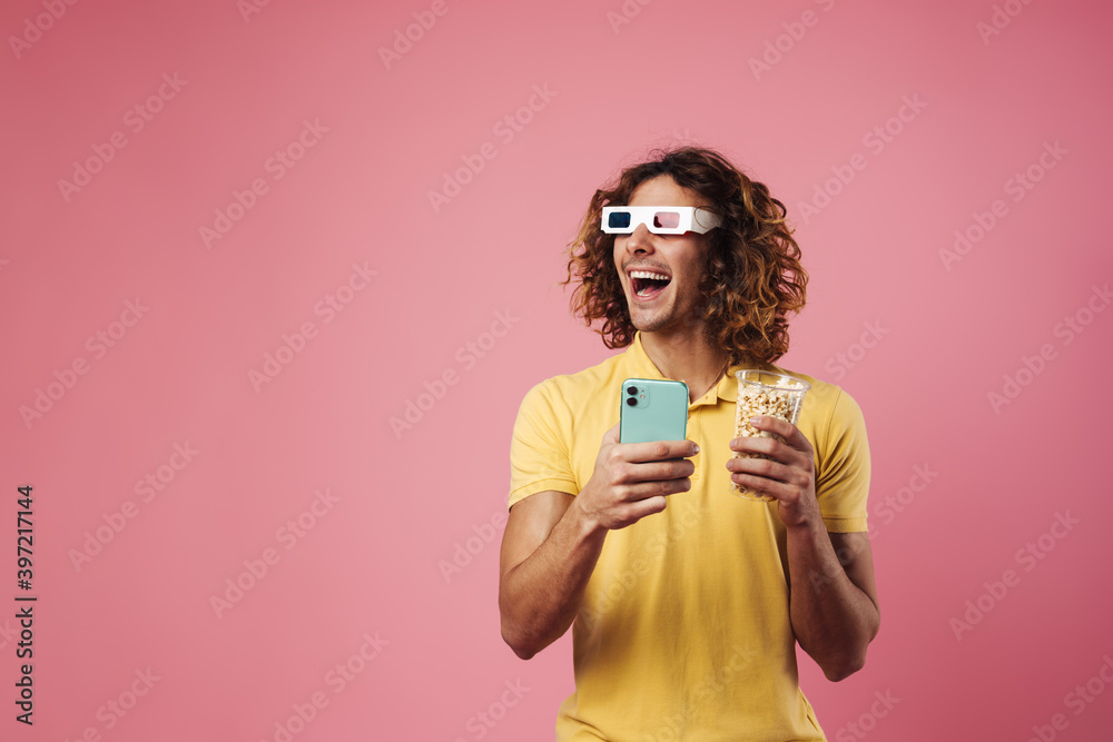 Excited handsome guy in 3d glasses using cellphone while watching movie Excited handsome guy in 3d glasses using cellphone while watching movie