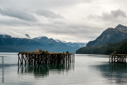 Shoreline, Cordova, Alaska. Old stake in the water. Mountains. Molo. photo