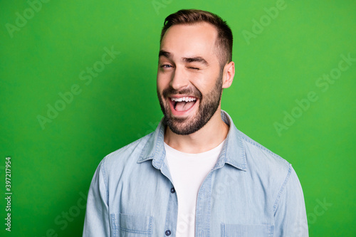 Portrait of optimistic man wear blue shirt blink open mouth isolated on green color background