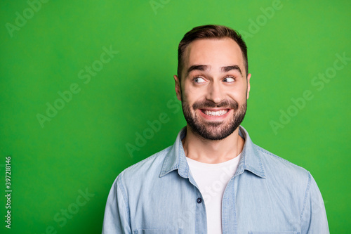 Portrait of optimistic funny man wear blue shirt look empty space isolated on green color background