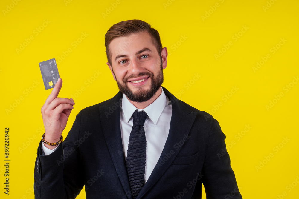 Portrait of handsome young businessman holding credit card over yellow background Portrait of handsome young businessman holding credit card over yellow background
