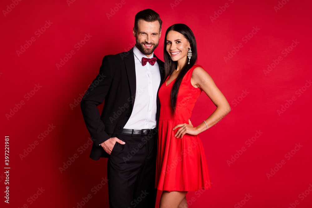 Photo of nice optimistic couple hug wear suit dress isolated on red color background Photo of nice optimistic couple hug wear suit dress isolated on red color background