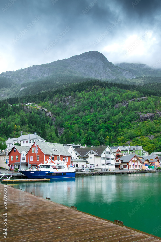 Odda, Norway. Norwegian landscape. Beautiful fjords. Cloudy and rainy day. Lake, mountains and classical Scandinavian houses