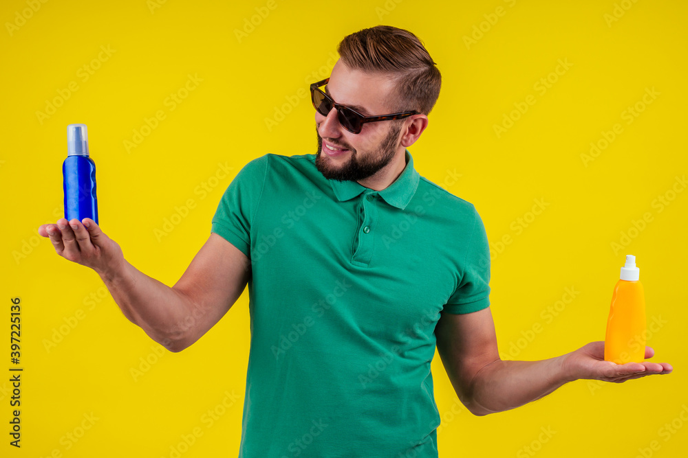 man holding bottle of sun cream in studio yellow background man holding bottle of sun cream in studio yellow background