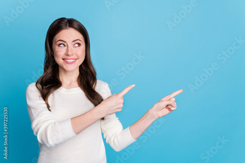 Photo of sweet charming curly woman dressed white pullover looking pointing two fingers empty space isolated blue color background
