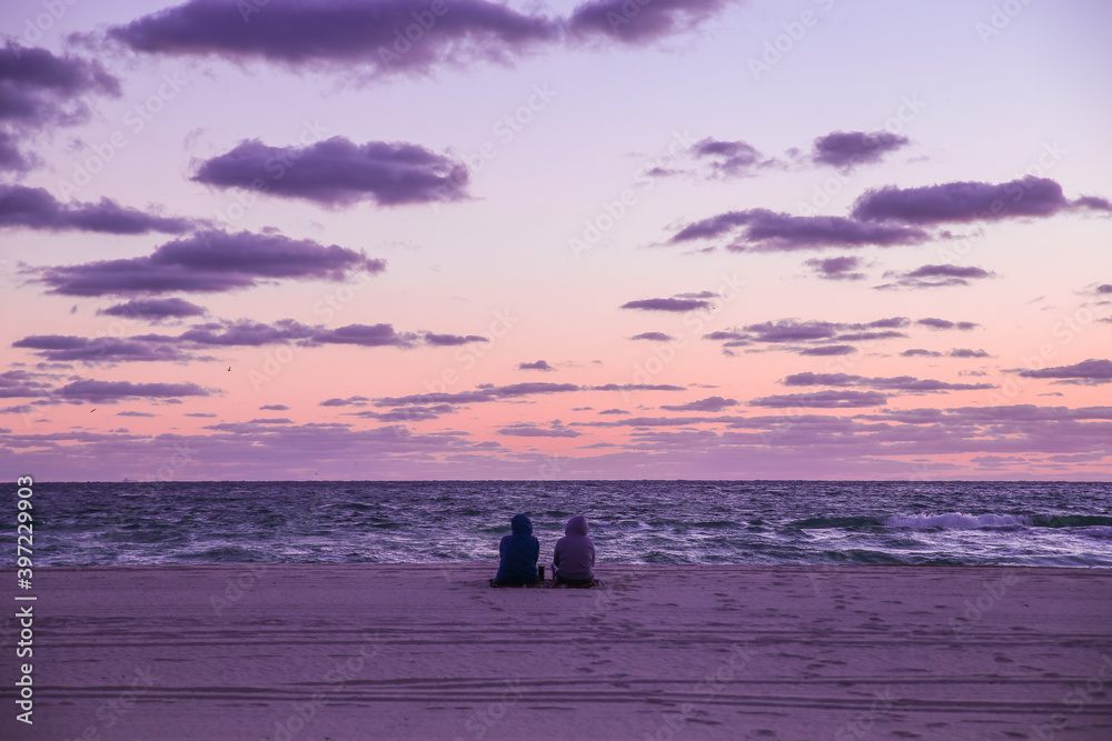 A couple enjoy a romantic morning in Miami, Florida as the sun rises over the Atlantic Ocean.