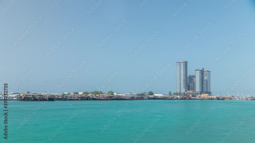 Traditional wooden fishing dhows berthed in the Dhow Harbour in Abu Dhabi timelapse, the capital city of the UAE. Modern skyscrapers on background. View from corniche Traditional wooden fishing dhows berthed in the Dhow Harbour in Abu Dhabi timelapse, the capital city of the UAE. Modern skyscrapers on background. View from corniche