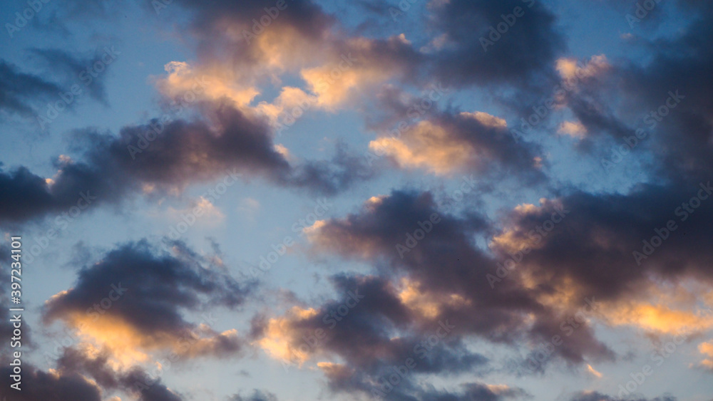 Magnifiques teintes orangées sous des petits amas de cumulus, pendant le coucher du soleil