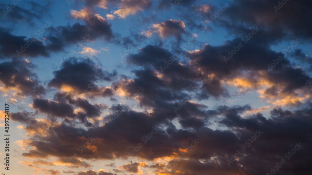 Magnifiques teintes orangées sous des petits amas de cumulus, pendant le coucher du soleil