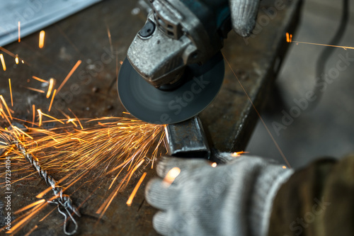 Grinding a metal part using an angle grinder. Many sparks fly out from under the disk