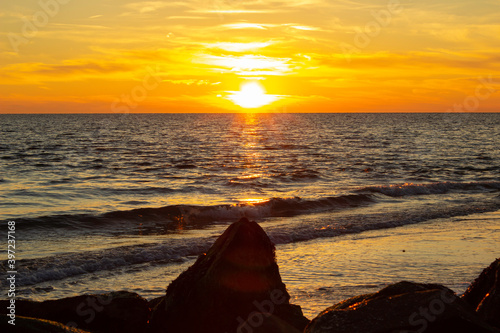 Beautiful sunset on the coast with stones on the beach