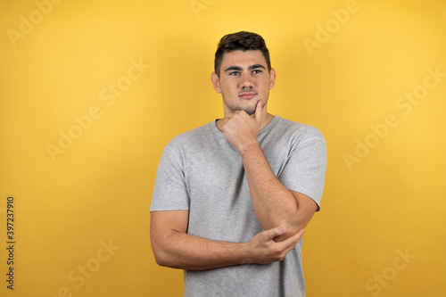 Young handsome man wearing a casual t-shirt over isolated yellow background looking to the side thoughtful