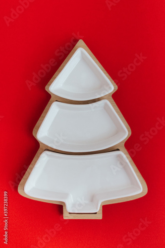 Empty plate in the shape of a Christmas tree on a red background.The view from the top.