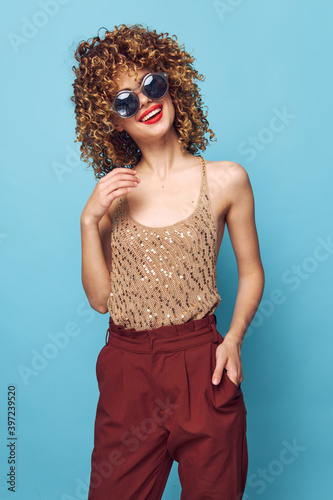 Portrait of a woman Curly hair red lips smile fashionable clothes blue background 
